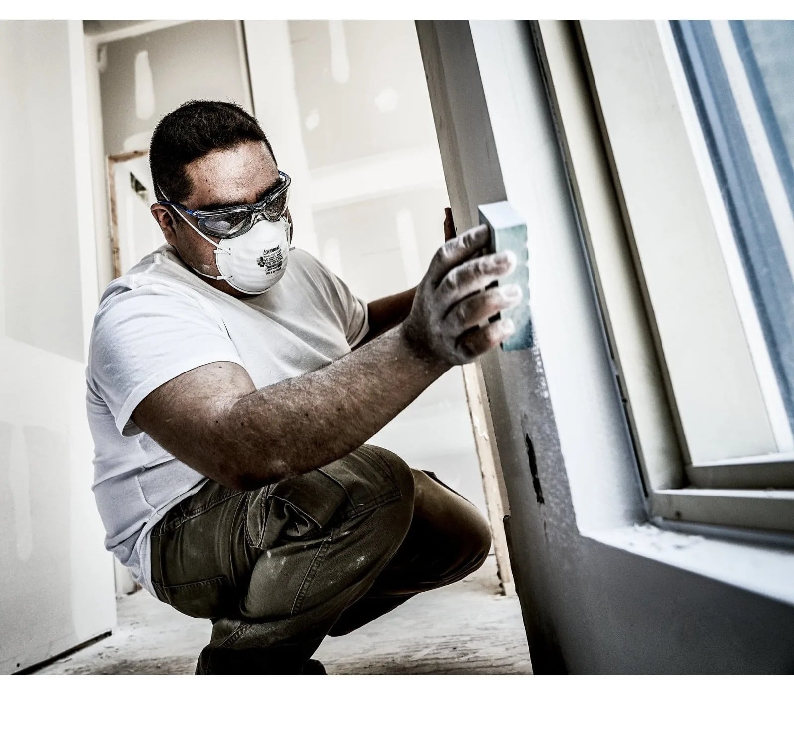 Worker wearing the 3M 8200 N95 respirator and safety glasses while sanding drywall