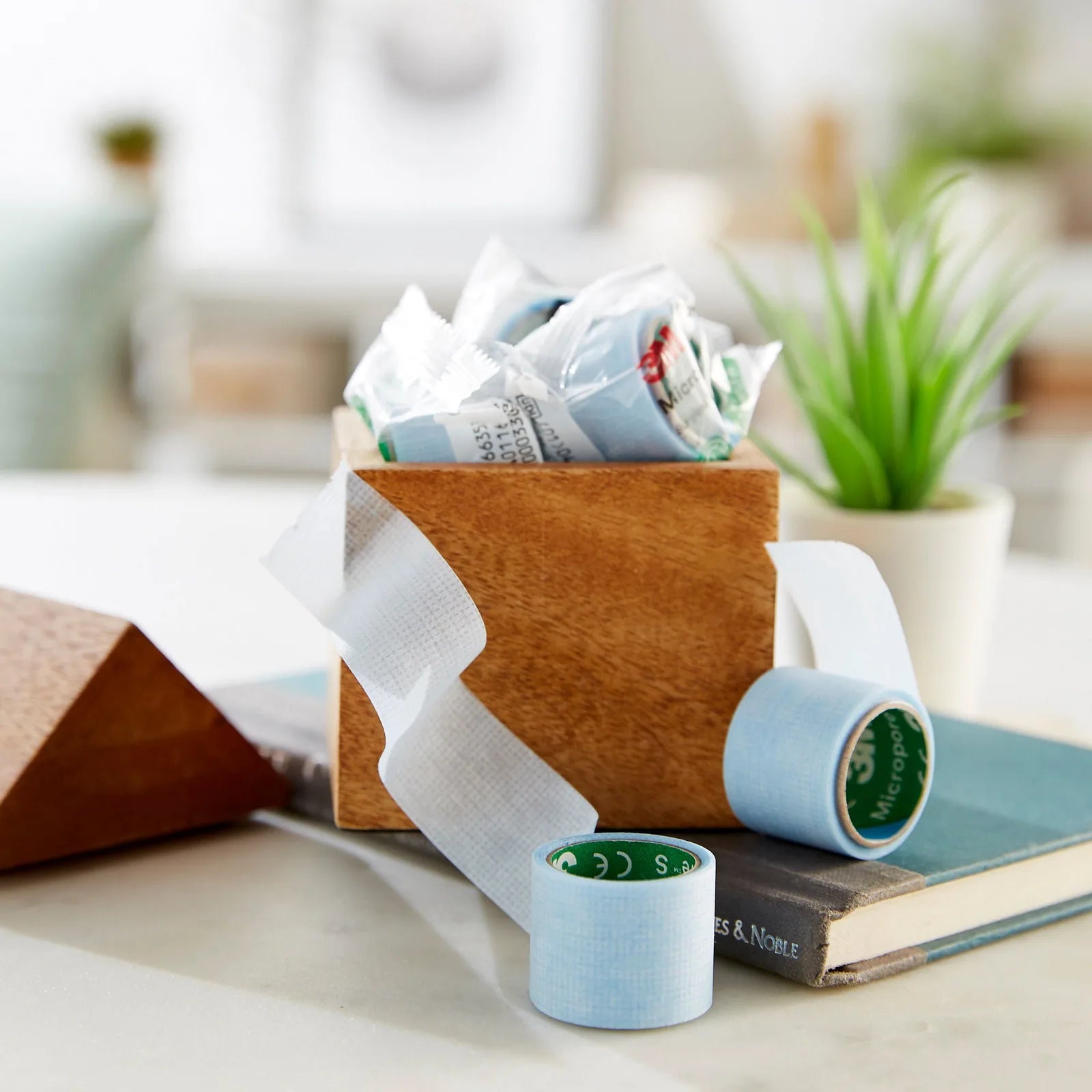 Rolls of 3M silicone surgical tape stored in a wooden box at home