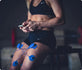 Athlete using PowerDot 2.0 Duo on knee for muscle recovery in gym